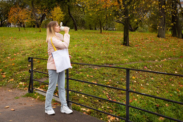 eco girl walking in park with coffee cup ang bag