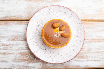 Sweet tartlets with almonds and caramel cream on a white wooden background. flat lay, close up.