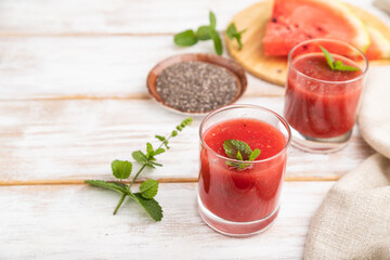 Watermelon juice with chia seeds and mint in glass on a white wooden background with linen textile. Side view, selective focus, copy space.
