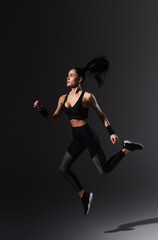Fototapeta na wymiar full length of sportive young woman flying on black
