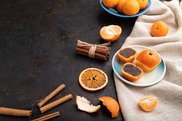 Truffle chocolate tangerine candies on a black concrete background. Side view, copy space.