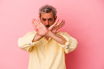 Middle age caucasian man isolated on pink background  doing a denial gesture