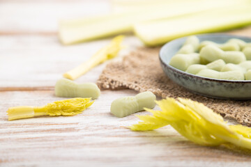 Jelly celery candies on white wooden background. side view, selective focus.