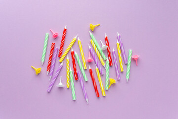 Flat lay of colorful birthday candles on lilac background, top view