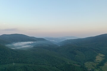 Obraz premium Peaks of the Carpathian Mountains at sunset. Sunset in the mountains, top view. Forest and mountains from a bird's eye view. Mountain range and valley.