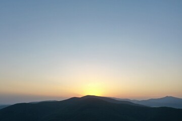Peaks of the Carpathian Mountains at sunset. Sunset in the mountains, top view. Forest and mountains from a bird's eye view. Mountain range and valley.