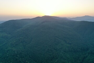 Peaks of the Carpathian Mountains at sunset. Sunset in the mountains, top view. Forest and mountains from a bird's eye view. Mountain range and valley.