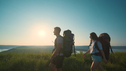 Fototapeta na wymiar The man and woman walking with backpacks on a blue sky background