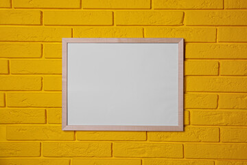 Empty frame on yellow brick wall. Mockup for design