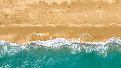 Fototapeta na wymiar Aerial top view from drone of blue ocean waves crashing on sandy beach
