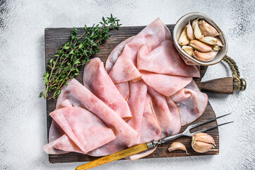 Ham Thin sliced on wooden cutting board with herbs. White background. Top view