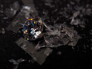 Close up shot of roud cut zircon zirconia gems with broken glass surrounded. Shoot on a black...