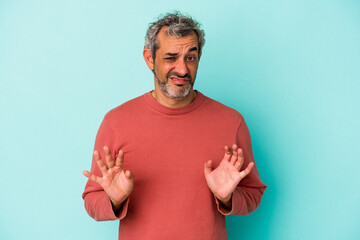 Middle age caucasian man isolated on blue background  rejecting someone showing a gesture of...
