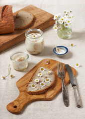 Homemade goose fat on a slice of fresh rye bread with edible daisy flowers. Selective focus. © Oksana Schmidt