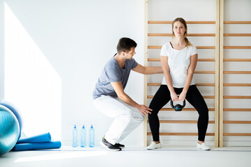 Professional physician helping his patient exercise with weights