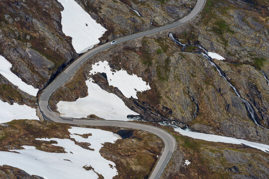 Curved road on the top of the mountain with snow next to it.