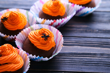 Halloween chocolate cupcakes with decor on wooden background