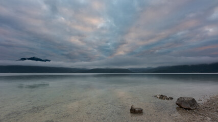 Fototapeta na wymiar The lake Walchensee in Bavaria on cold misty morning with windless calm water