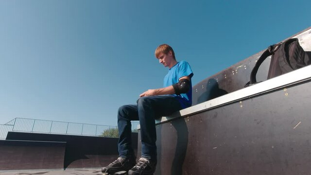 Putting on protection in skate park man outdoors