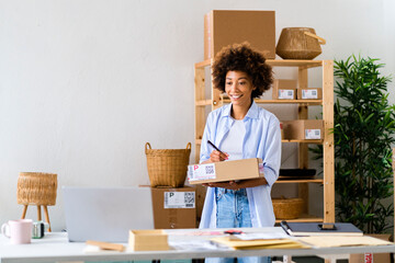 Smiling female entrepreneur writing on box while working at studio