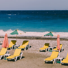 Beach with yellow sunbeds and colorful umbrellas, sea with waves. Retro styled concept - 459453549