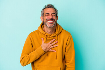 Fototapeta premium Middle age caucasian man isolated on blue background laughs out loudly keeping hand on chest.