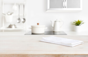 Fototapeta na wymiar White napkin on table with blurred kitchen cooking zone background