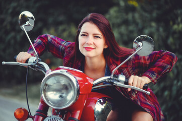 Fototapeta na wymiar The biker is a beautiful cheerful girl sitting on her motorcycle, a little crazy. Wear short shorts. holding the steering wheel the wind blows the hair. Looks into the distance at the road