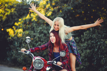 Fototapeta na wymiar Young beautiful women ride a retro motorcycle. A talented girl in a blue overalls. They push the motorcycle, the merry go to the road. sale of spare parts. Place for text