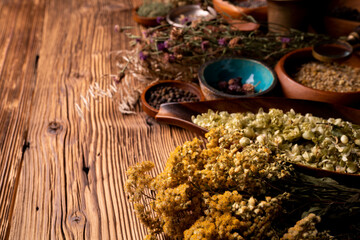 Natural medicine background. Assorted dry herbs in bowls and brass mortar on rustic wooden table.