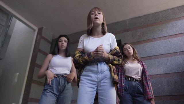 Bottom view of three aggressive Caucasian teenage girls talking threatening someone. Portrait of adolescent schoolgirls bullying. Adolescence and aggression concept