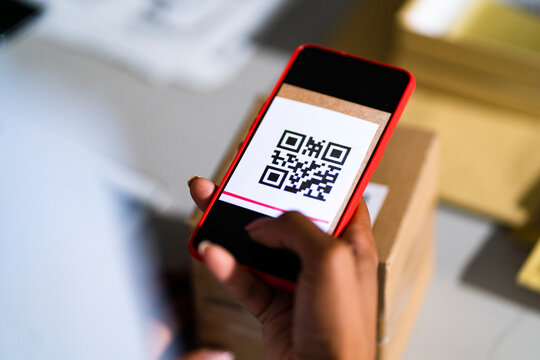 Young businesswoman scanning barcode through mobile phone