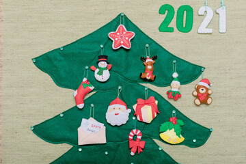 A part of felt handmade Christmas tree shaped, with toys and number 2021. Concept children fun, diy.