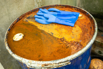 Rusty barrel at the harbour and blue gloves