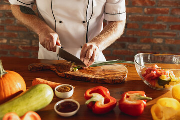 Close-up male chef's hands, cook cutting fresh vegetable salad in his cafe, restaurant kitchen. Concept of a correct, healthy diet.