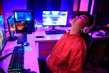 Asian gamer playing online game on PC in dark room, tired gamer sleep while playing game he away from keyboard, AFK. e-Sport Games compilation © Kannapat