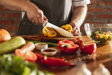 Close-up hands of male chef, cook cutting fresh vegetable salad in his cafe, restaurant kitchen. Concept of a correct, healthy diet.