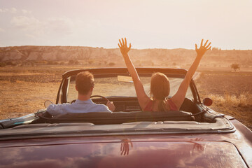 happy couple driving vintage classic sport car at sunset, luxury lifestyle