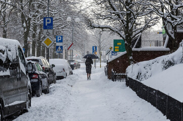 WINTER ATTACK - A woman with an umbrella is walking along the snowy pavement 
