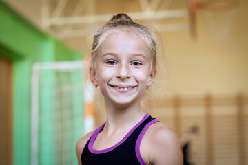 Portrait of smiling girl gymnast in gym