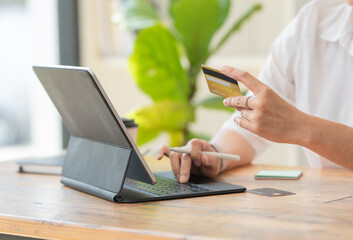 Fototapeta premium Close-up woman's hands holding a credit card and using computer