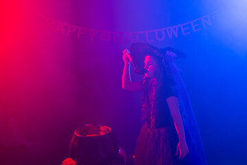 Fototapeta na wymiar Little witch child cooking potion in the cauldron on Halloween.