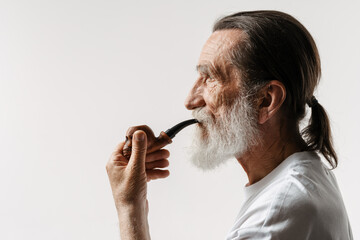 European senior man looking aside while posing with smoking pipe