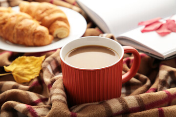 Hot coffee with croissant and autumn leaves on plaid - seasonal relax concept