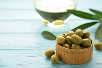 Olive oil with olive on blue wooden background with copy space.