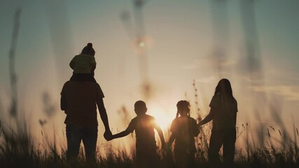 Happy family at sunset. Silhouette of group of people walk in park. Happy child with parents holding hand. Family is walk in park on grass. Happy family concept. Parents hold hand of their child. - Powered by Adobe