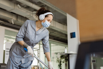 White cleaning woman in headphones washing floor with mop