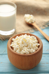 Cottage cheese and milk for breakfast in bowl on blue background. Vertical photo
