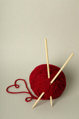 Ball of yarn with knitting needles on light gray background