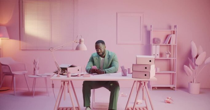 Happy startup creator smiling enjoying smartphone phone game app or message news network at work office with monochrome pink pastel design room studio monocolor creative office with monochrome design
